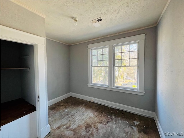 unfurnished bedroom featuring visible vents, crown molding, a textured ceiling, and baseboards