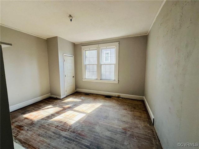 spare room featuring crown molding, baseboards, and wood finished floors