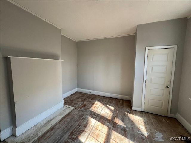 unfurnished room featuring crown molding, baseboards, and wood finished floors