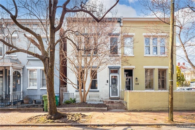 multi unit property featuring brick siding and a fenced front yard