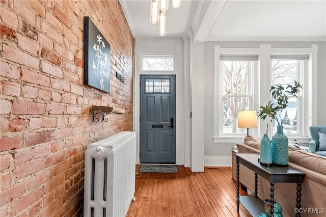 entrance foyer with a healthy amount of sunlight, brick wall, and radiator heating unit