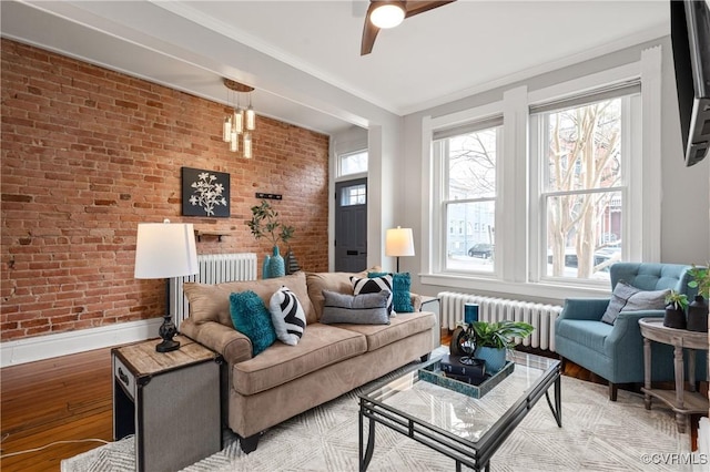 living area with brick wall, radiator heating unit, light wood-type flooring, and a wealth of natural light