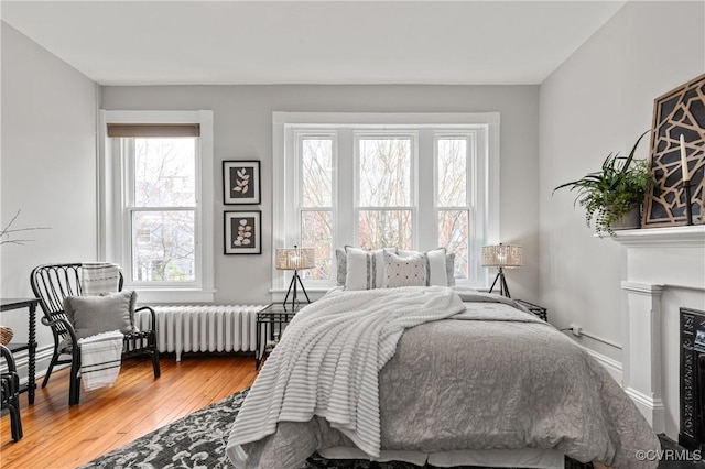 bedroom featuring radiator, baseboards, and hardwood / wood-style flooring