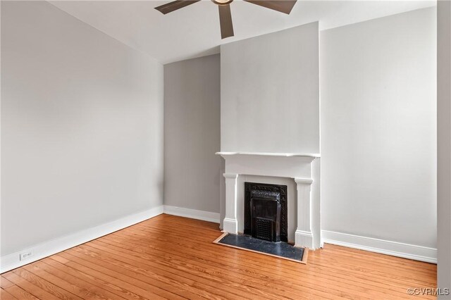 unfurnished living room with ceiling fan, baseboards, wood finished floors, and a fireplace with flush hearth