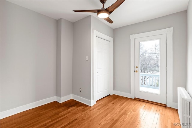 interior space featuring ceiling fan, baseboards, radiator heating unit, and light wood-style floors