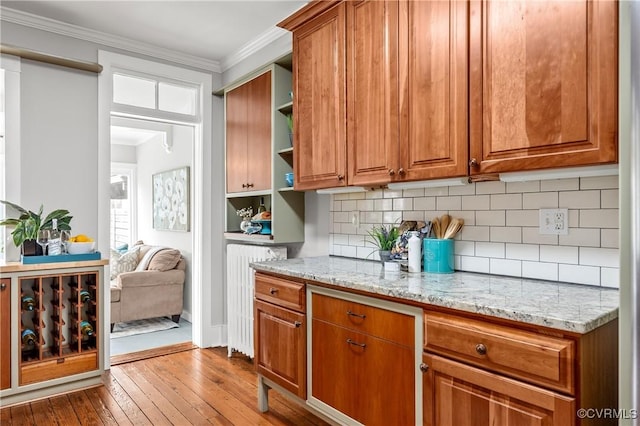 kitchen with light stone countertops, hardwood / wood-style floors, crown molding, and open shelves