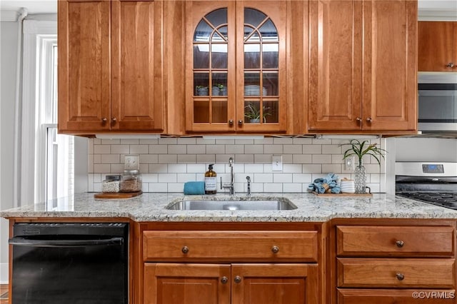 kitchen with glass insert cabinets, tasteful backsplash, appliances with stainless steel finishes, and a sink