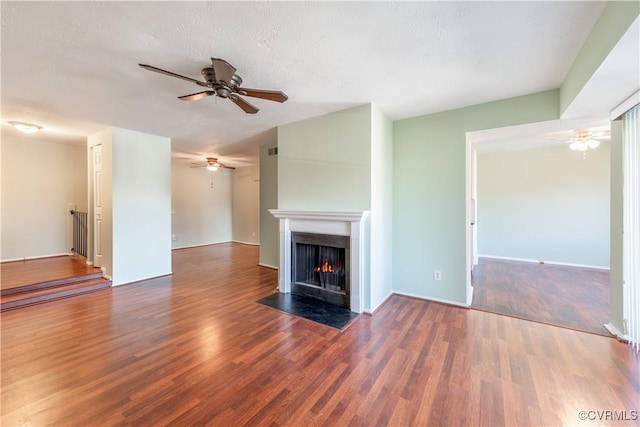 unfurnished living room with a fireplace with flush hearth, a textured ceiling, wood finished floors, and a ceiling fan