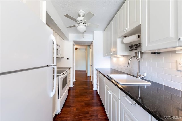 kitchen featuring tasteful backsplash, dark wood-type flooring, white cabinets, white appliances, and a sink