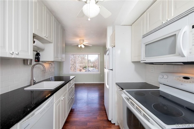 kitchen with white appliances, ceiling fan, a sink, white cabinetry, and dark countertops