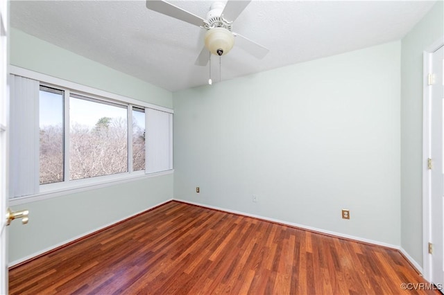 empty room featuring a ceiling fan, wood finished floors, baseboards, and a textured ceiling