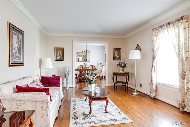 living room featuring baseboards, an inviting chandelier, ornamental molding, and light wood finished floors