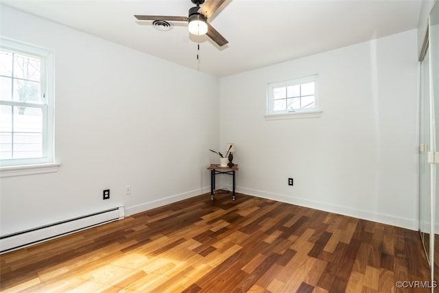 unfurnished room with ceiling fan, baseboard heating, wood finished floors, and baseboards