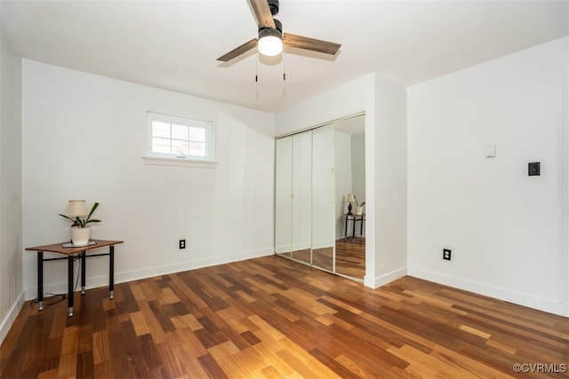 unfurnished bedroom with ceiling fan, a closet, wood finished floors, and baseboards