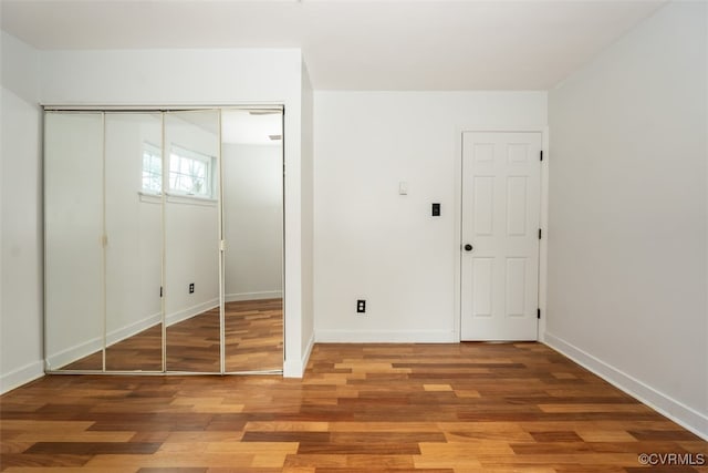 unfurnished bedroom featuring a closet, baseboards, and wood finished floors