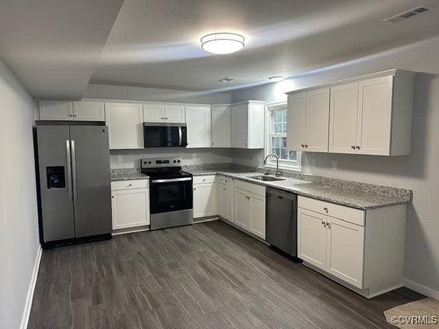 kitchen with stainless steel appliances, dark wood finished floors, a sink, and visible vents