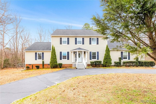 colonial-style house with crawl space, roof with shingles, and driveway