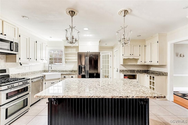 kitchen with appliances with stainless steel finishes, light tile patterned floors, a sink, and an inviting chandelier