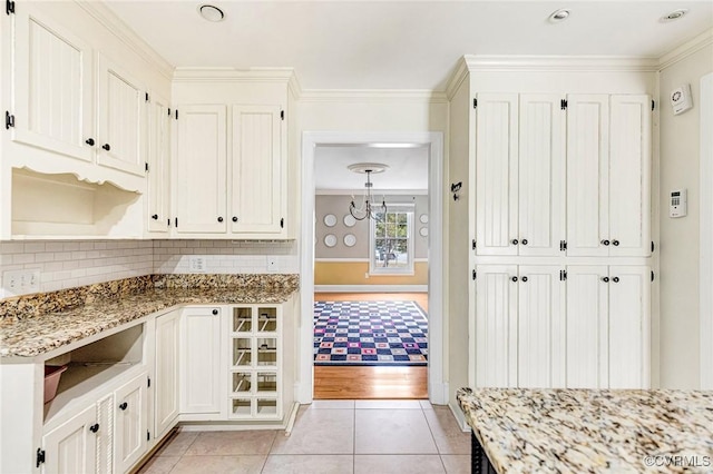 kitchen featuring light tile patterned floors, backsplash, light stone countertops, open shelves, and crown molding