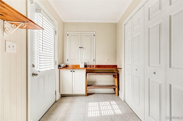 doorway with light tile patterned flooring and crown molding