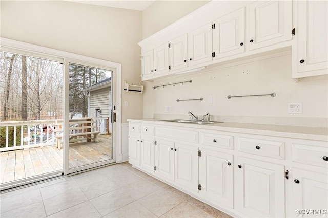 kitchen featuring white cabinets, light countertops, a sink, and light tile patterned flooring