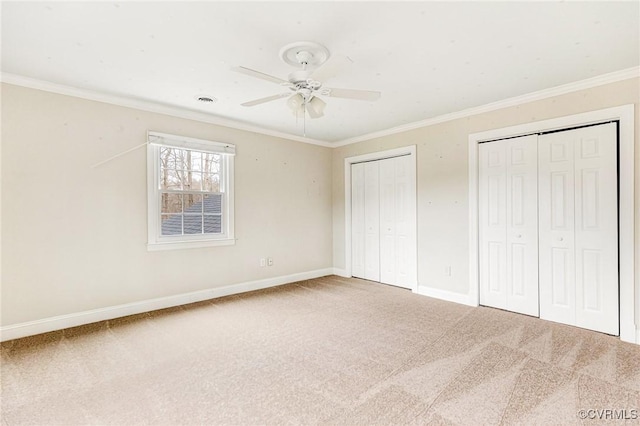 unfurnished bedroom with baseboards, carpet, ornamental molding, and two closets