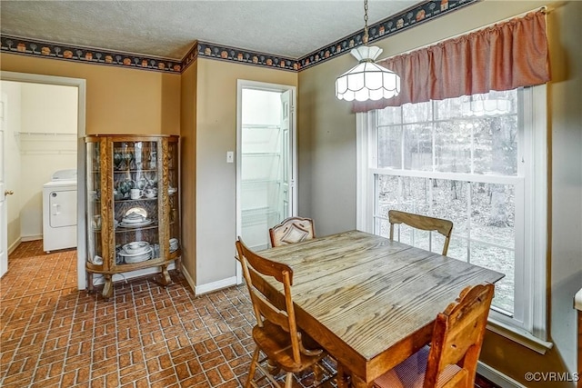 dining area with washer / dryer, baseboards, brick floor, a textured ceiling, and a wealth of natural light