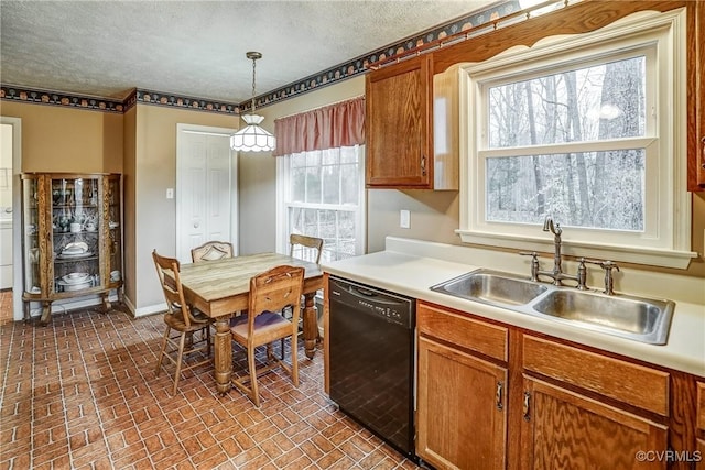 kitchen with black dishwasher, decorative light fixtures, brick floor, light countertops, and a sink