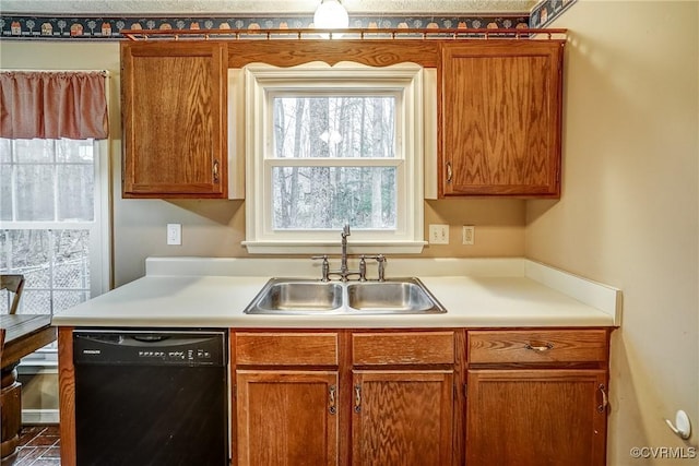 kitchen with black dishwasher, light countertops, brown cabinetry, and a sink