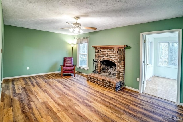 unfurnished room with baseboards, plenty of natural light, wood finished floors, and a brick fireplace