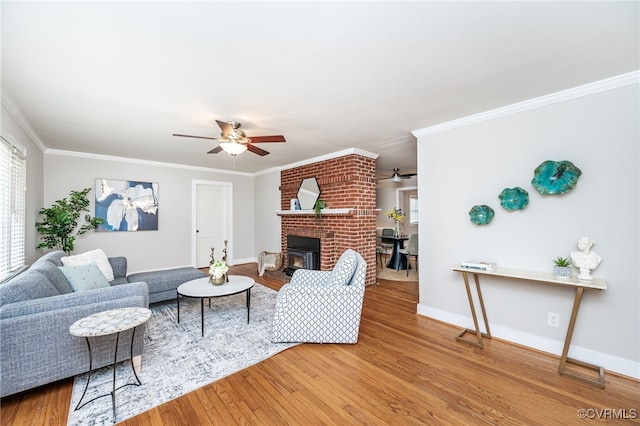 living area featuring baseboards, ceiling fan, ornamental molding, and wood finished floors