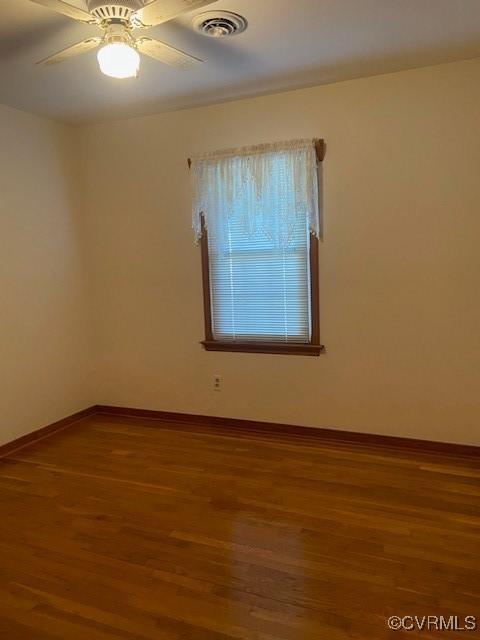 unfurnished room featuring visible vents, ceiling fan, baseboards, and wood finished floors