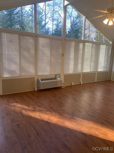 unfurnished sunroom featuring a ceiling fan and a wall mounted air conditioner