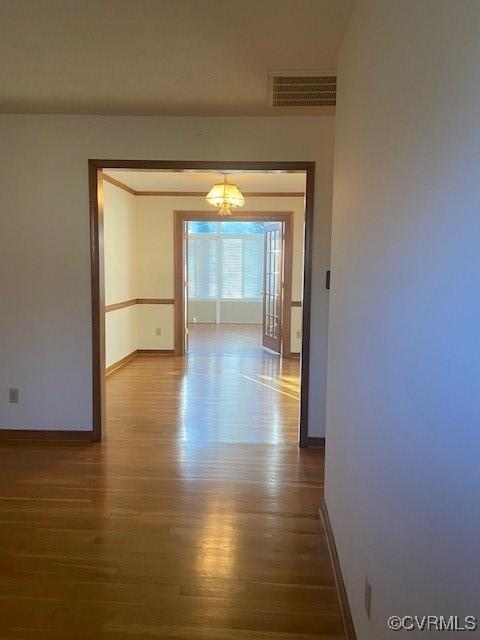 corridor with visible vents, baseboards, and wood finished floors