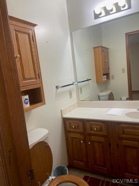 half bath featuring vanity, toilet, and tile patterned floors