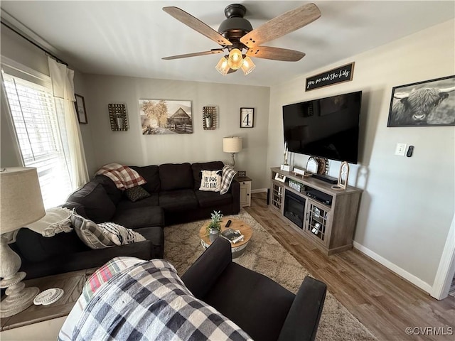 living area featuring ceiling fan, baseboards, and wood finished floors