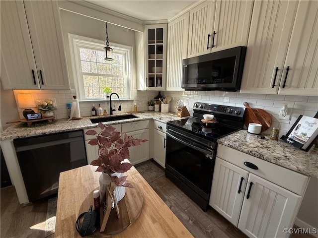 kitchen with black appliances, backsplash, and a sink