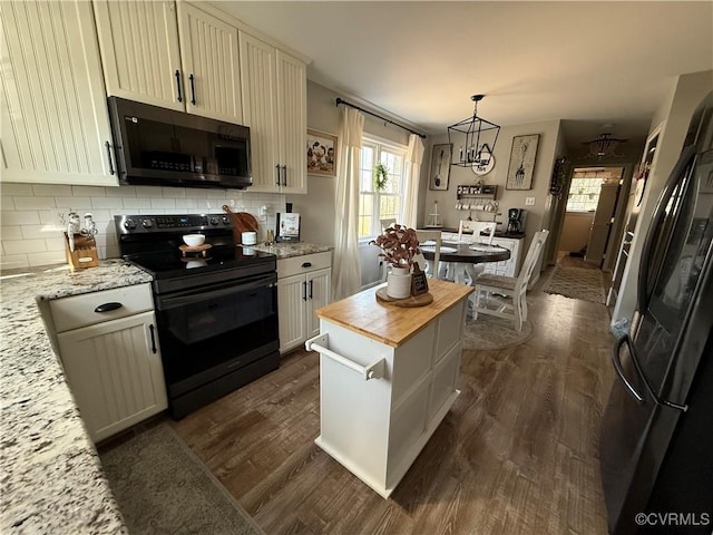 kitchen with tasteful backsplash, black appliances, dark wood-style floors, and hanging light fixtures