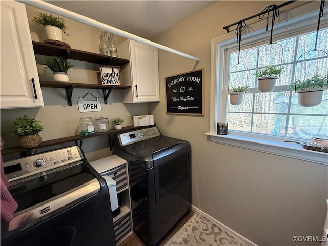 laundry area featuring washing machine and clothes dryer, cabinet space, and baseboards