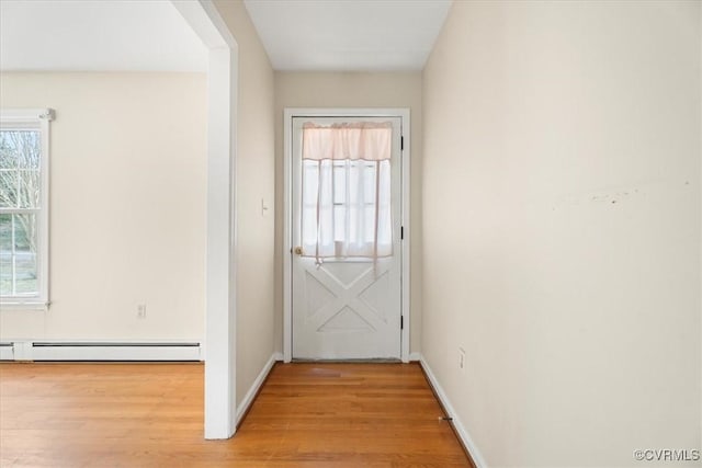 doorway to outside featuring light wood-style floors, baseboards, and a baseboard heating unit