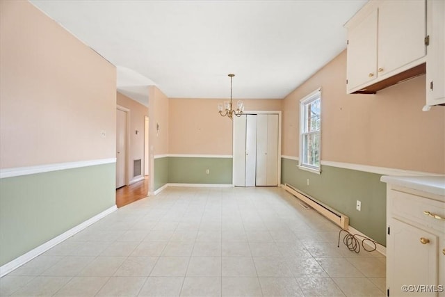 spare room featuring an inviting chandelier, visible vents, a baseboard heating unit, and baseboards