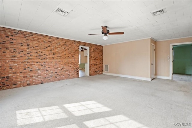 carpeted empty room with brick wall, visible vents, and crown molding