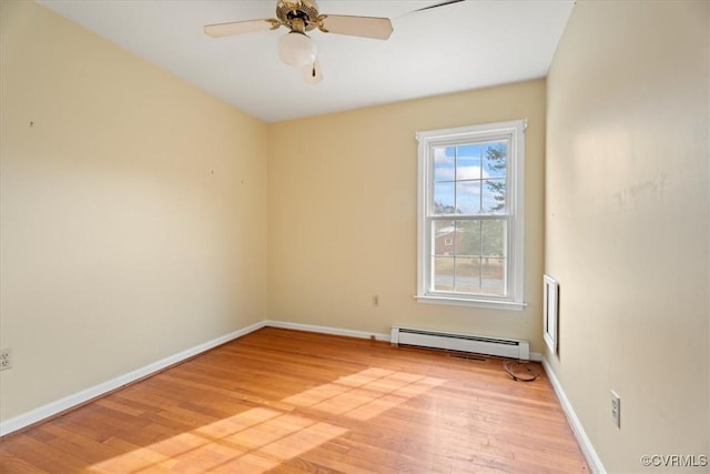 spare room with a baseboard heating unit, ceiling fan, baseboards, and light wood-style floors