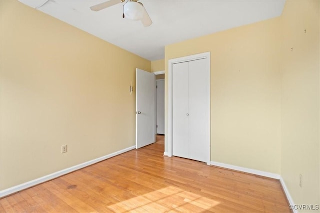 unfurnished bedroom featuring a ceiling fan, light wood-style flooring, baseboards, and a closet