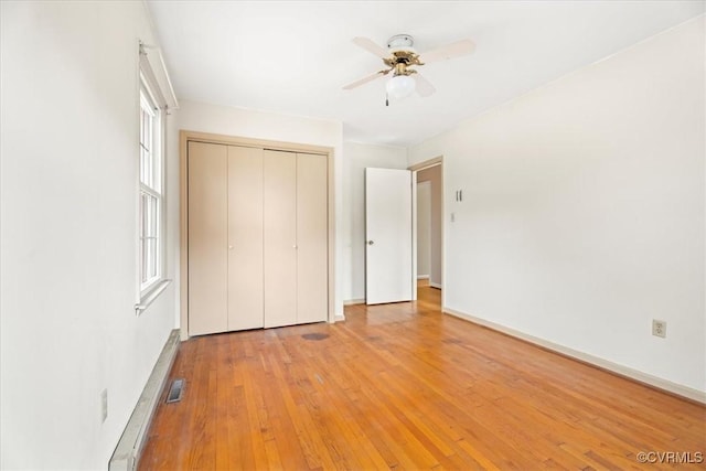unfurnished bedroom featuring ceiling fan, visible vents, baseboards, a closet, and light wood finished floors