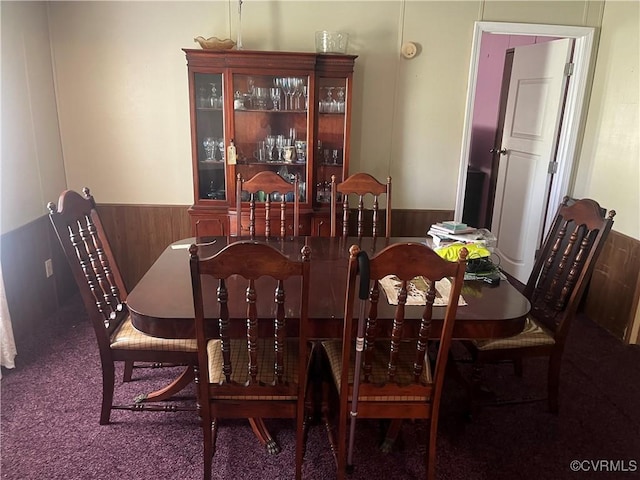 dining space featuring wooden walls, carpet, and wainscoting