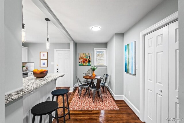 dining area featuring baseboards and dark wood-type flooring