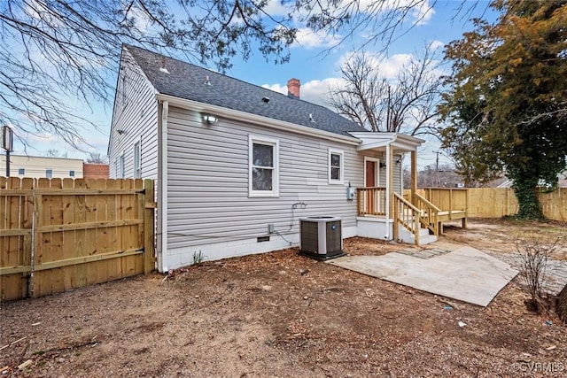 back of house with a shingled roof, a chimney, crawl space, fence, and cooling unit