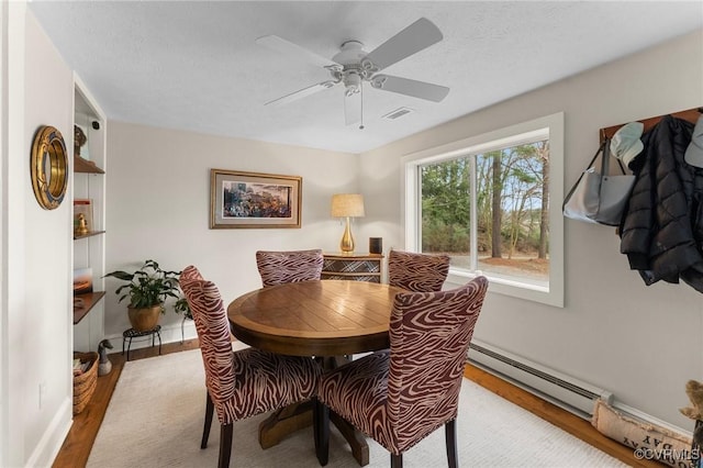 dining area with baseboards, visible vents, a baseboard radiator, wood finished floors, and a textured ceiling