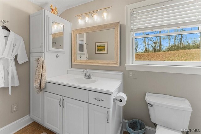 bathroom featuring toilet, baseboards, and vanity